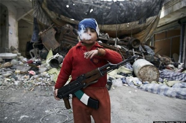 Trong ảnh là một chiến binh phe nổi loạn tại Syria. Chỉ mới 8 tuổi nhưng em đã biết cầm súng AK47 và hút thuốc lá. Sâu thẳm trong đôi mắt em có lẽ là sự gào thét đau đớn bất lực vì bị tước đi những tháng ngày ngây ngô nhất do chiến tranh.